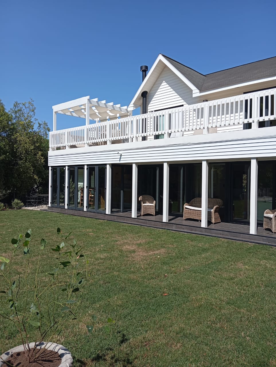 Casa de dos pisos con terraza y pérgola ampliada